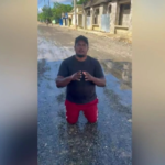 Regidor del PRM Manoli Montero de rodillas en una calle sin asfaltar de Pimentel, provincia Duarte, solicitando ayuda al presidente Luis Abinader.