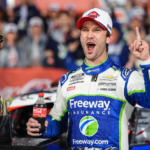 El piloto mexicano Daniel Suárez celebrando emocionado junto a su auto bajo la lluvia tras ganar el Coca-Cola 600 en Charlotte.