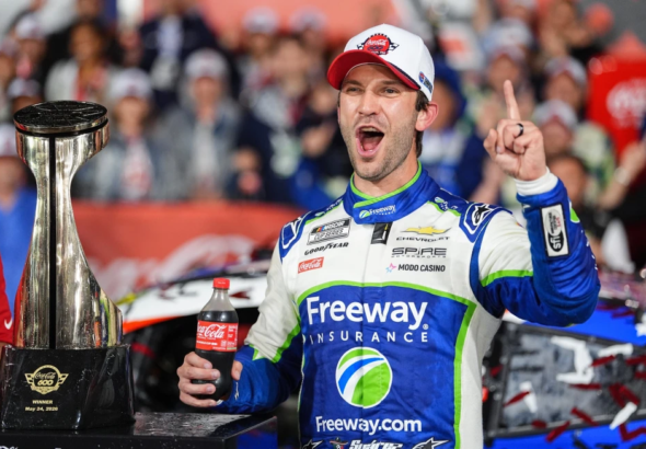 El piloto mexicano Daniel Suárez celebrando emocionado junto a su auto bajo la lluvia tras ganar el Coca-Cola 600 en Charlotte.