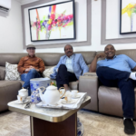 Los exalcaldes Manuel Jiménez con gorra, José Montás en el centro con chaqueta azul, y José Andújar a la derecha sonriendo en un sofá durante una reunión privada en una residencia.