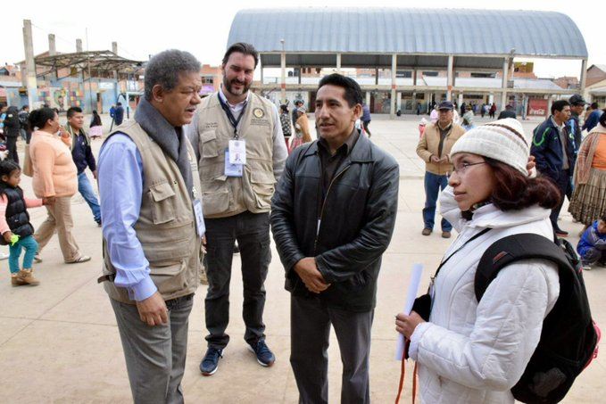 El expresidente dominicano Leonel Fernández, jefe de la Misión de la OEA, conversa con ciudadanos y delegados internacionales en el centro de votación de una plaza pública de El Alto, Bolivia.