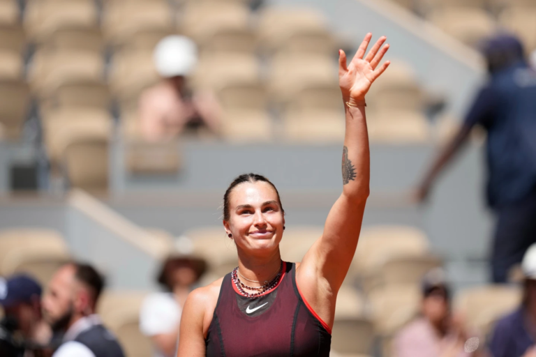 La tenista Aryna Sabalenka realiza un golpe de derecha en la pista Philippe-Chatrier reflejando el brillo de sus collares de diamantes bajo el sol de París.
