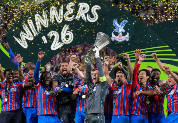 El delantero Jean-Philippe Mateta junto a sus compañeros del Crystal Palace levantando el trofeo de campeones de la UEFA Conference League en el podio de Leipzig, rodeados de confeti y celebrando de manera eufórica.