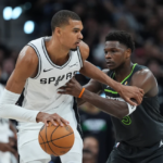 Victor Wembanyama celebrando un remate en el aire frente a la defensa de los Timberwolves; marcador de fondo reflejando la ventaja de San Antonio.