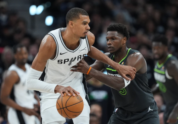 Victor Wembanyama celebrando un remate en el aire frente a la defensa de los Timberwolves; marcador de fondo reflejando la ventaja de San Antonio.
