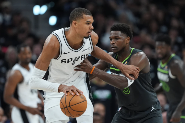 Victor Wembanyama celebrando un remate en el aire frente a la defensa de los Timberwolves; marcador de fondo reflejando la ventaja de San Antonio.