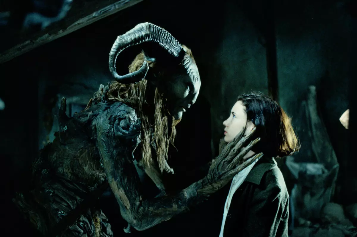 Fotograma icónico de la película mostrando a la niña Ofelia frente al Fauno en las ruinas del laberinto de piedra