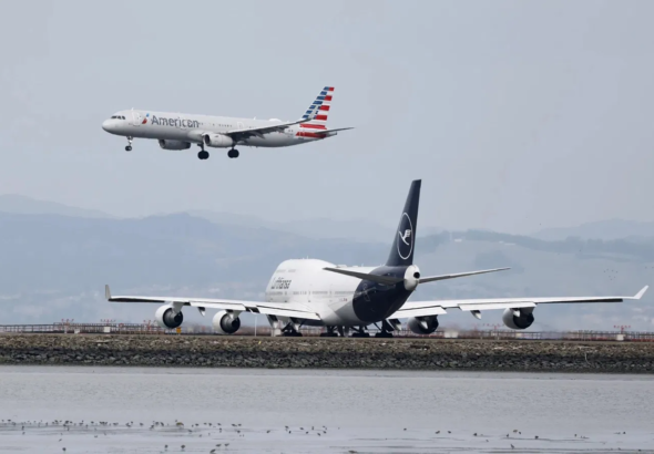 Avión de American Airlines aterrizando junto a aeronave de Lufthansa en pista aeroportuaria.