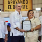 El presidente Luis Abinader entregando un certificado de título definitivo a una comunitaria del municipio Pepillo Salcedo.