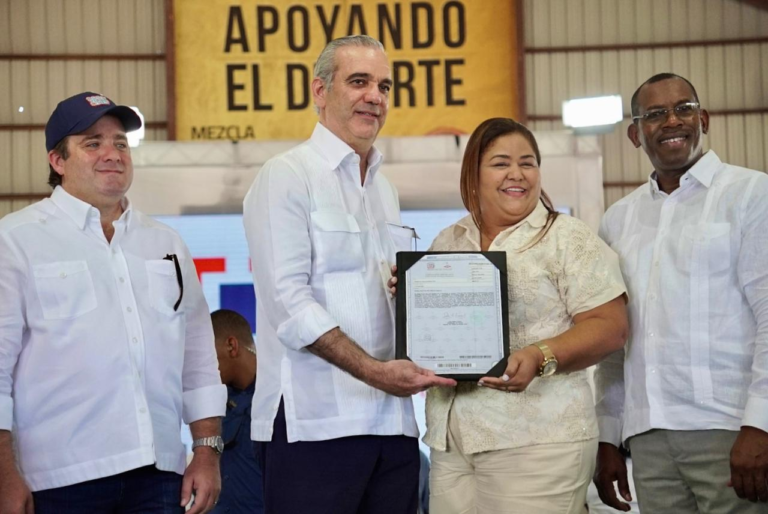 El presidente Luis Abinader entregando un certificado de título definitivo a una comunitaria del municipio Pepillo Salcedo.