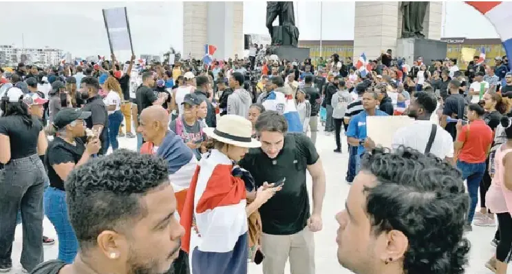 Vista de la Plaza de la Bandera en Santo Domingo abarrotada de ciudadanos con pancartas y banderas dominicanas durante una protesta pacífica.