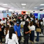 Cientos de jóvenes haciendo fila con currículums en mano durante la feria de empleo en el campus de la PUCMM