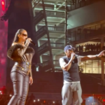 La cantante barbadense Rihanna cantando con un micrófono junto al rapero Jay-Z sobre el escenario iluminado del Yankee Stadium en Nueva York.