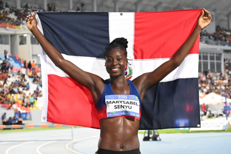 La atleta dominicana Marysabel Senyú celebrando con la bandera tras ganar la medalla de oro en salto alto.