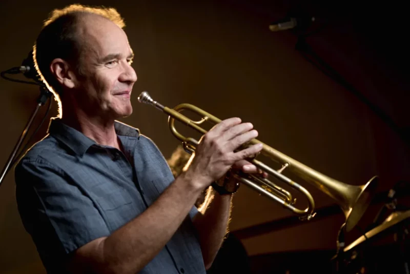 El trompetista de jazz Chris Kase califica la música con inteligencia artificial como un engaño y critica las fallas en la formación musical actual.